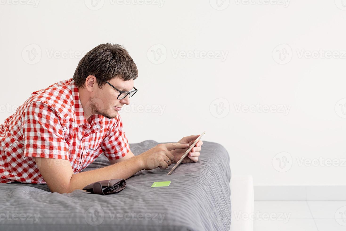 junger Mann mit Tablet im Internet einkaufen foto