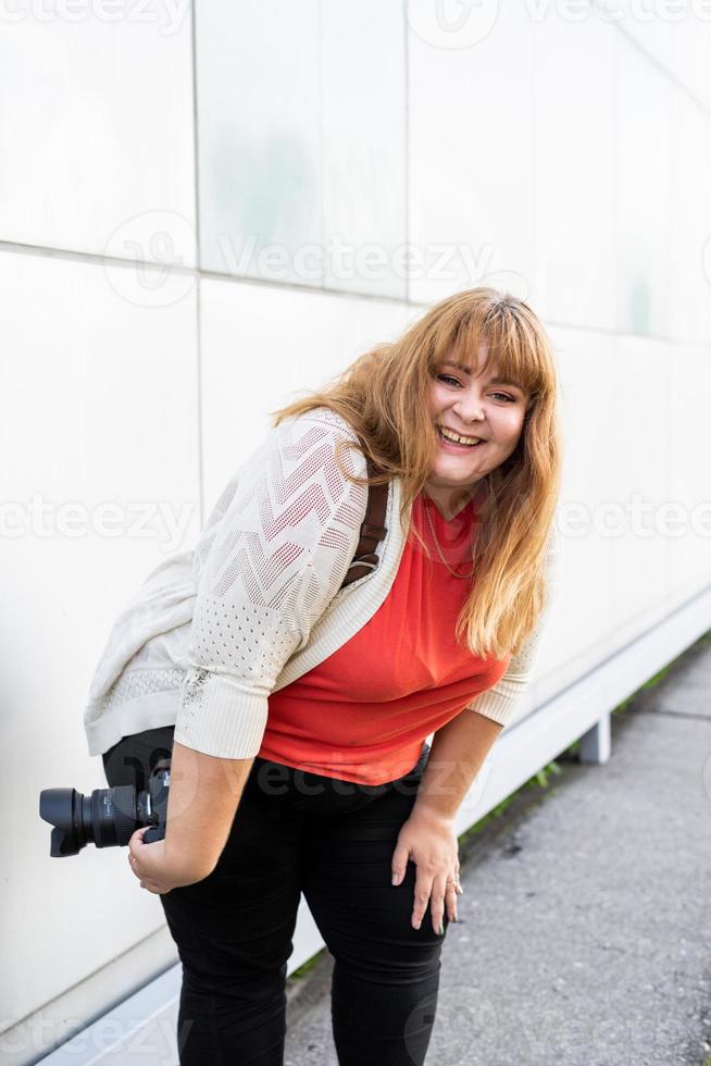 Porträt einer übergewichtigen Frau, die im Freien Bilder mit einer Kamera macht foto
