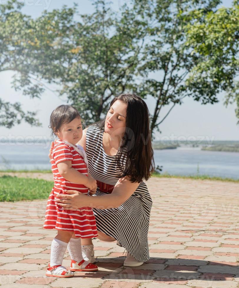 glückliche gemischtrassige Familie von Mutter und Tochter, die im Park spazieren gehen foto