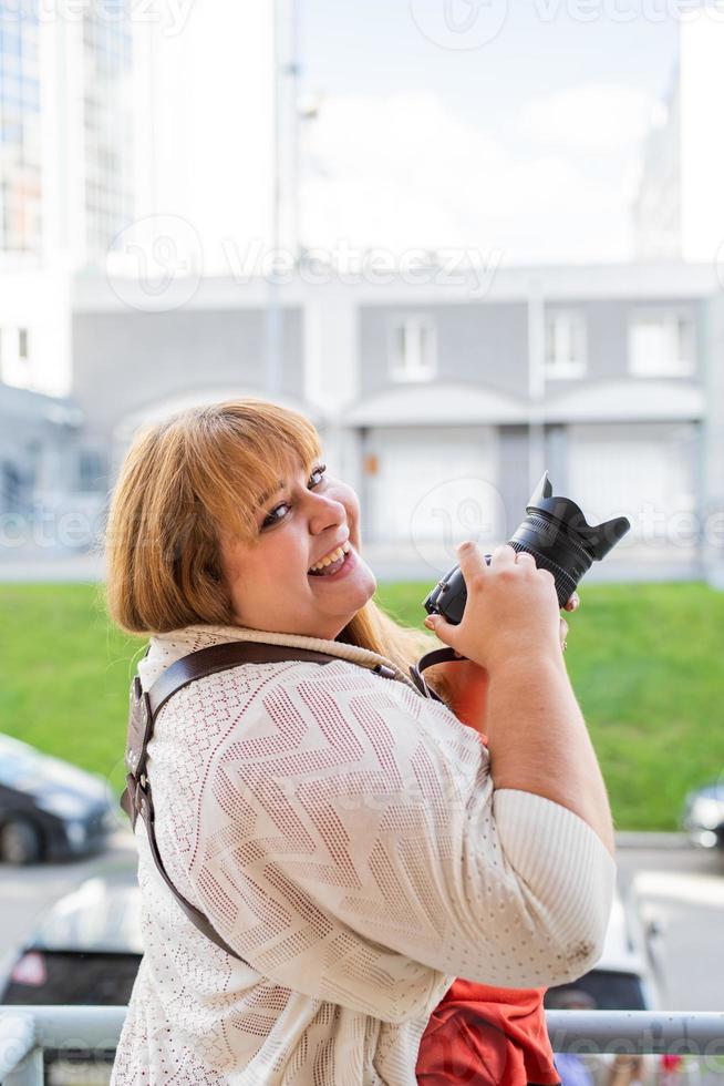 Porträt einer übergewichtigen Frau, die im Freien Bilder mit einer Kamera macht foto