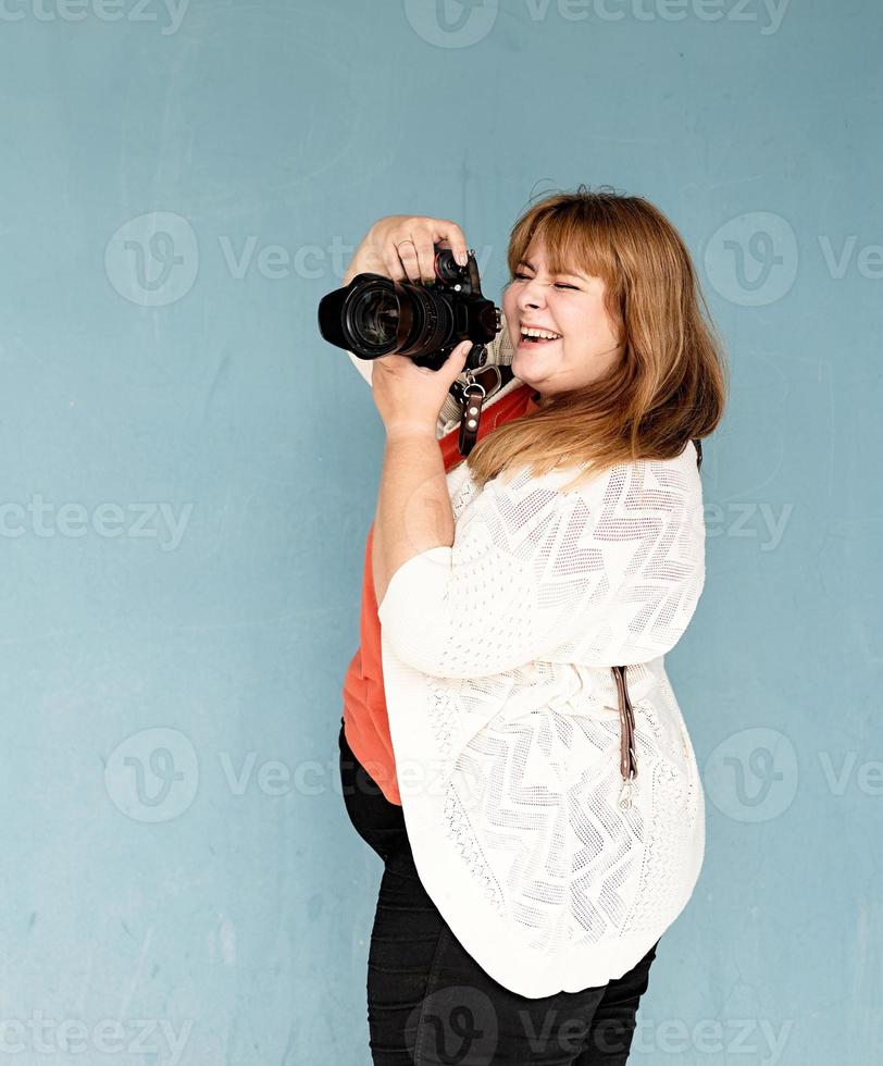 Plus-Size-Frauenfotograf im Freien auf blauem einfarbigem Hintergrund foto