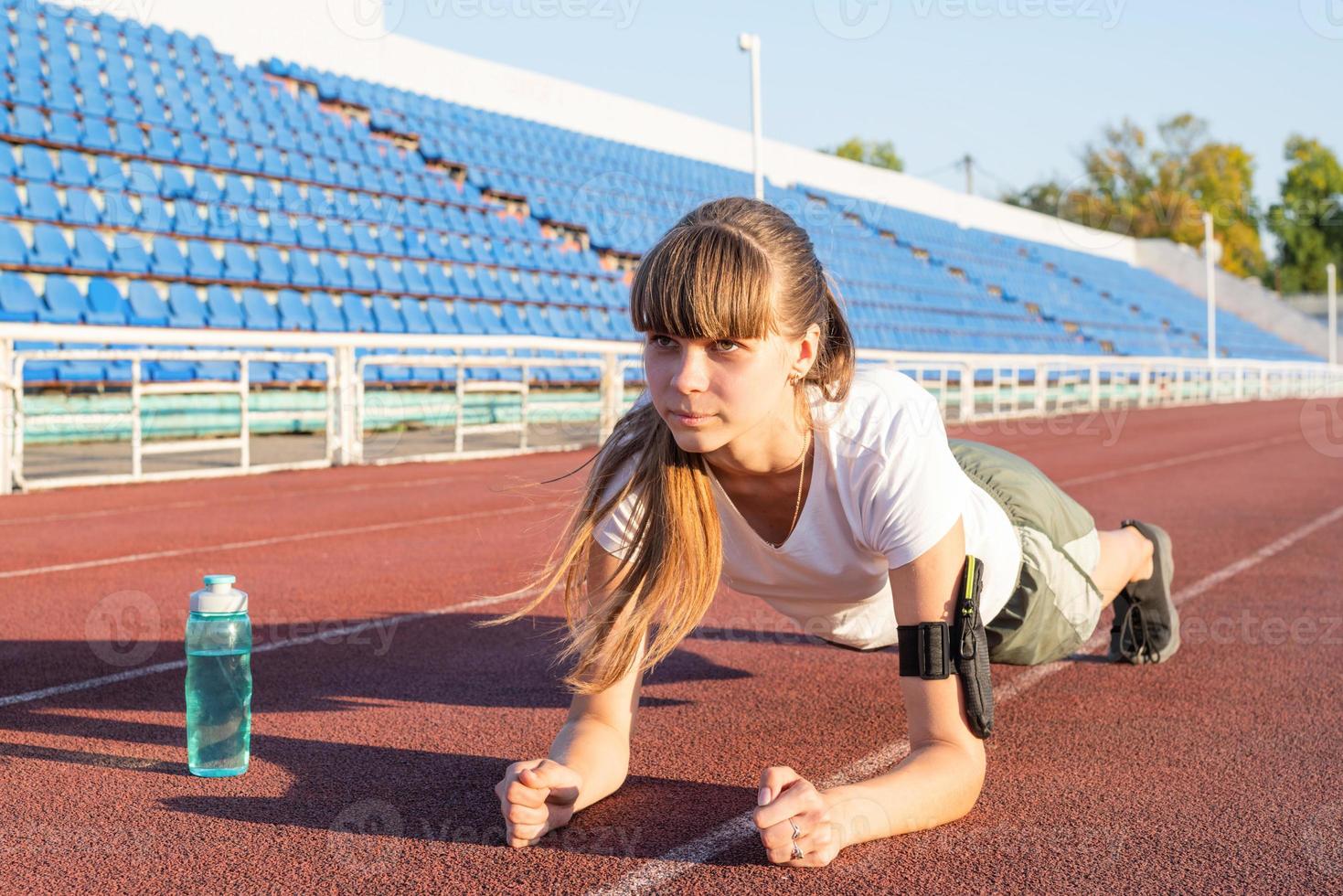 Teenager-Mädchen in einer Plankenposition beim Training im Stadion foto