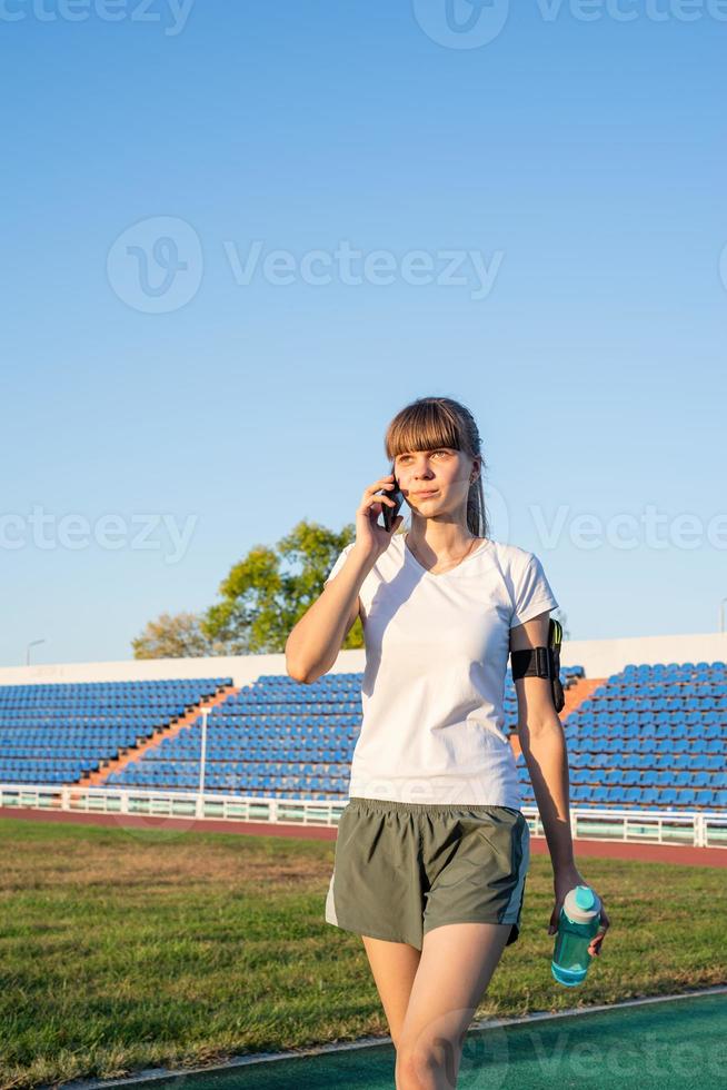 junge Sportlerin telefoniert im Stadion foto