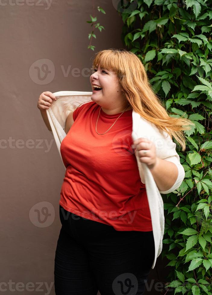 Übergewichtige Frau posiert auf der braunen festen Wand auf der Straße foto