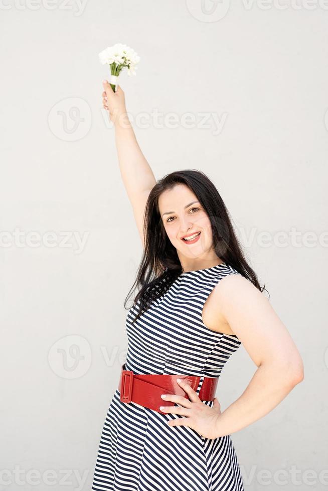 junge Frau mit einem Blumenstrauß in erhobener Hand auf grauem Hintergrund foto