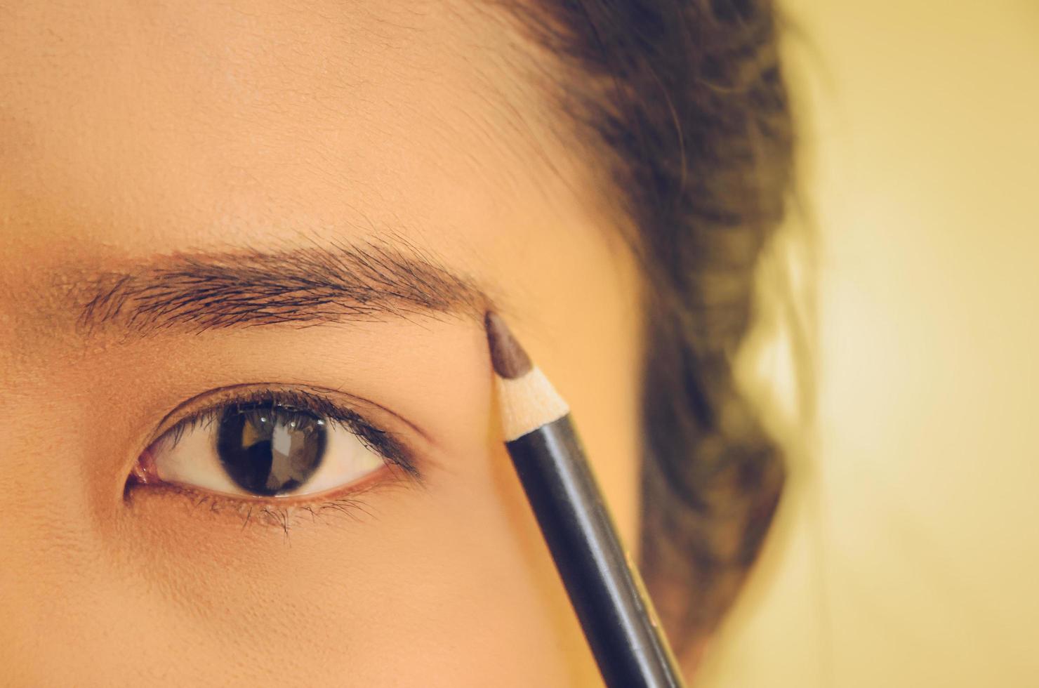 Schönheitsgesicht der asiatischen Frau durch Auftragen des Augenbrauenstiftes auf die Haut. foto