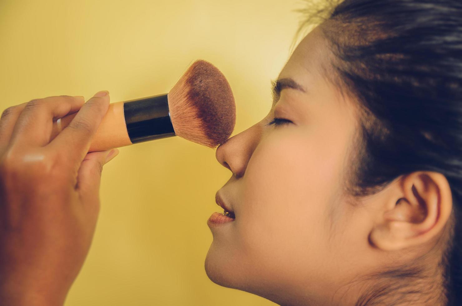 Schönheitsgesicht der asiatischen Frau durch Auftragen von Bürsten auf die Haut durch Kosmetik. foto