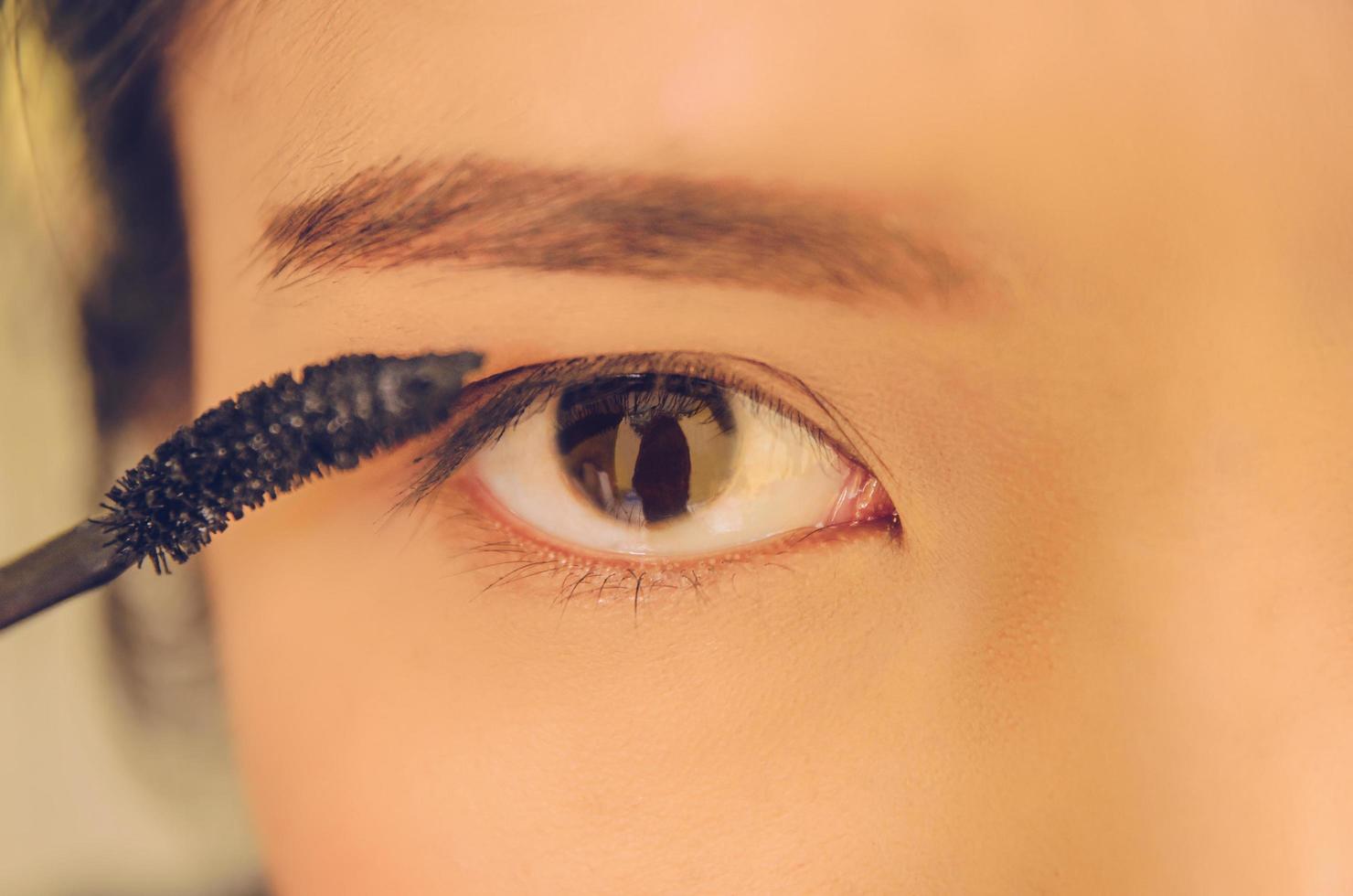 Schönheitsgesicht der Frau durch Auftragen von Wimperntusche auf das Auge durch Kosmetik. foto