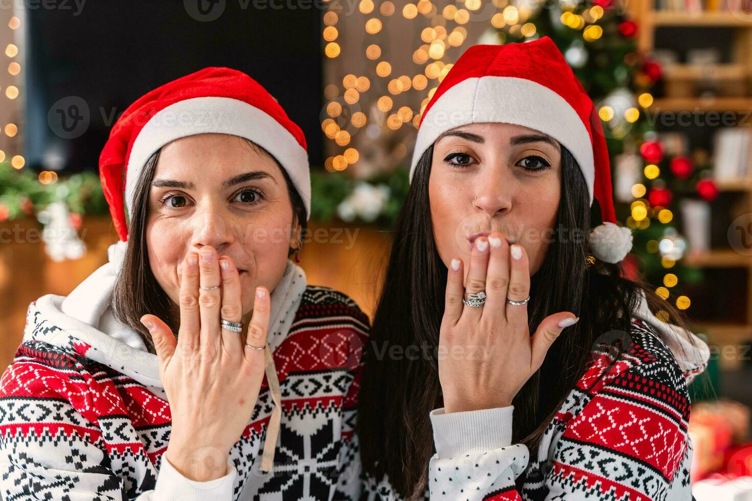 süß jung Frauen gekleidet im rot Hut und Weihnachten Sweatshirt weht ein Kuss foto