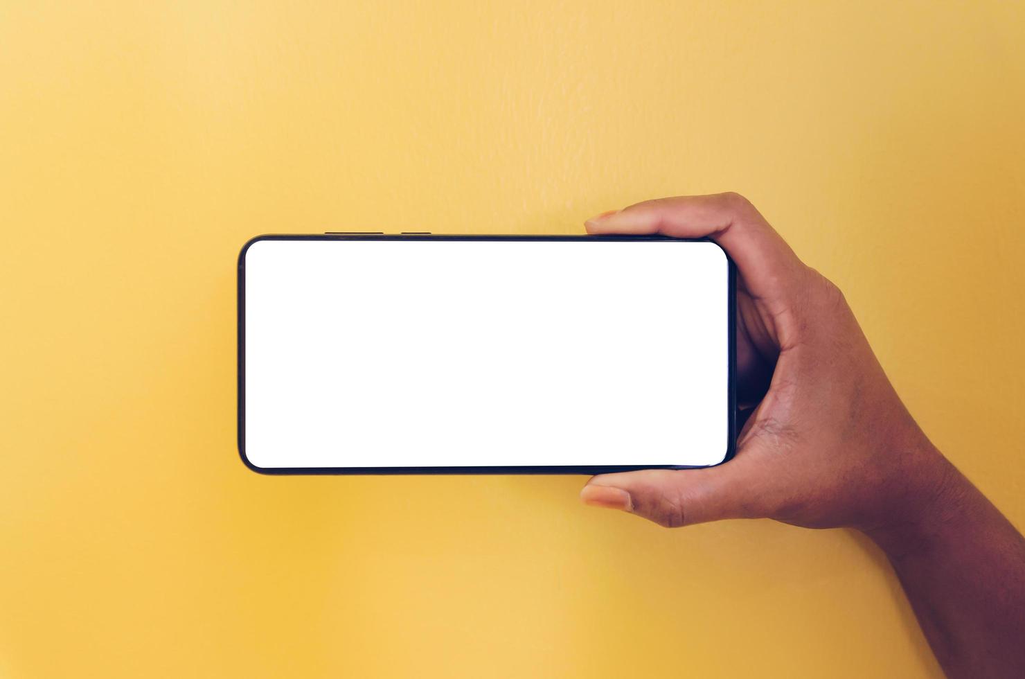 eine Hand, die Smartphone mit weißem Bildschirmhintergrund hält. foto