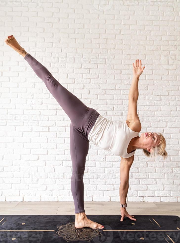 blonde Frau, die zu Hause Yoga praktiziert foto