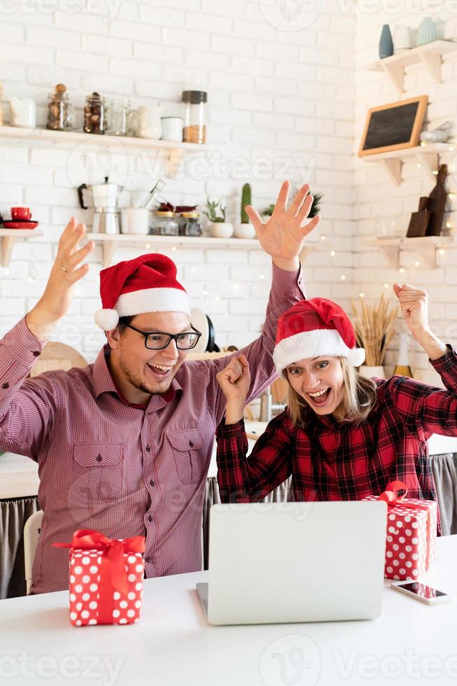 Paar in Weihnachtsmützen begrüßt seine Freunde in einem Videoanruf foto