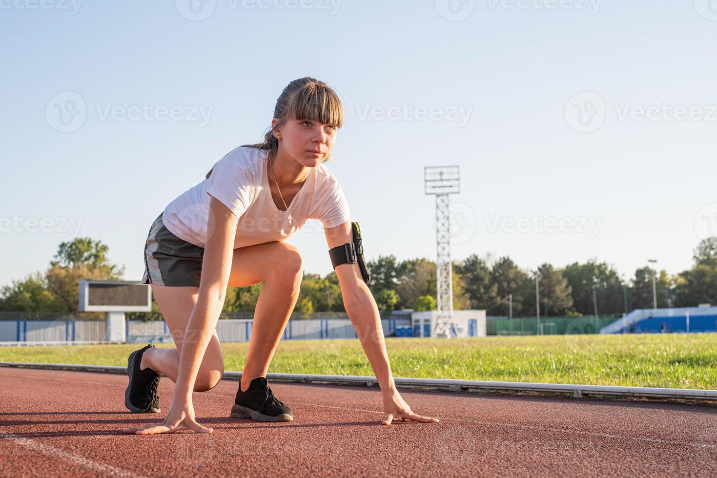 Frau auf Startposition, Vorbereitung zum Laufen auf der Stadionbahn foto