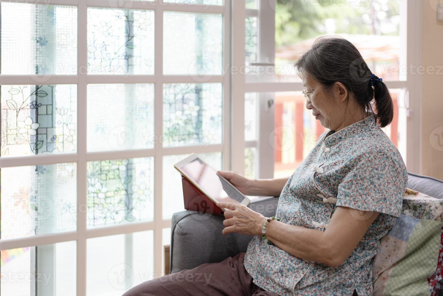 Reife Frau mit Tablet zum Lesen zu Hause foto