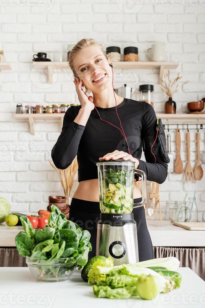 Frau macht grünen Smoothie zu Hause in der Küche foto