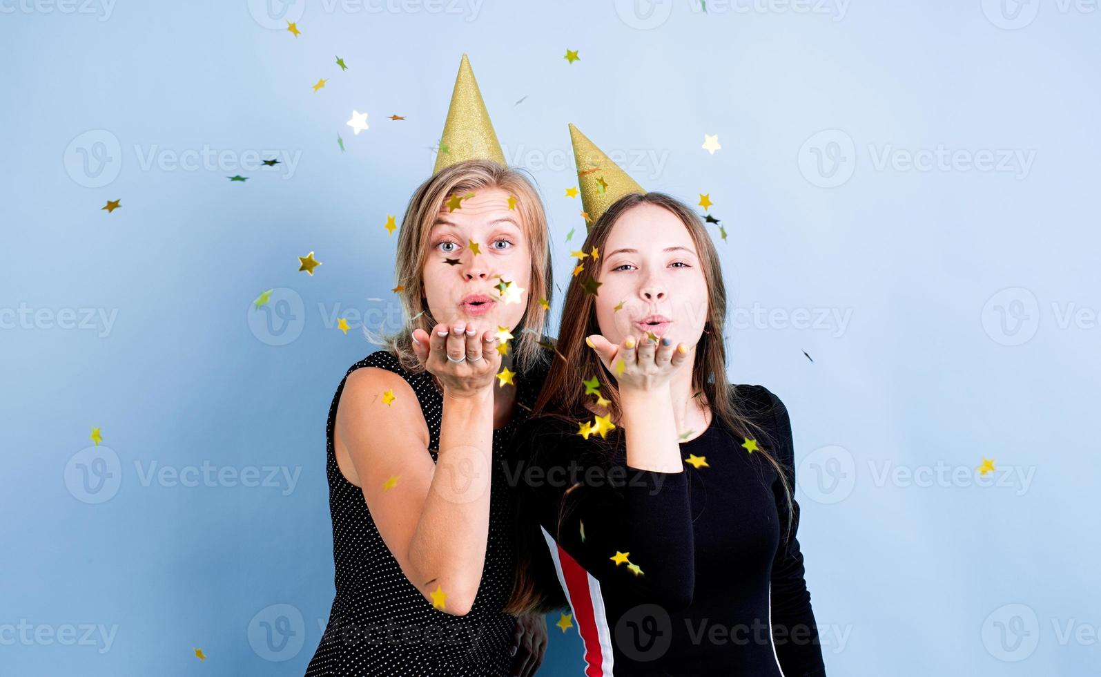 junge Frauen, die Luftballons halten, die Geburtstag über blauem Hintergrund feiern foto