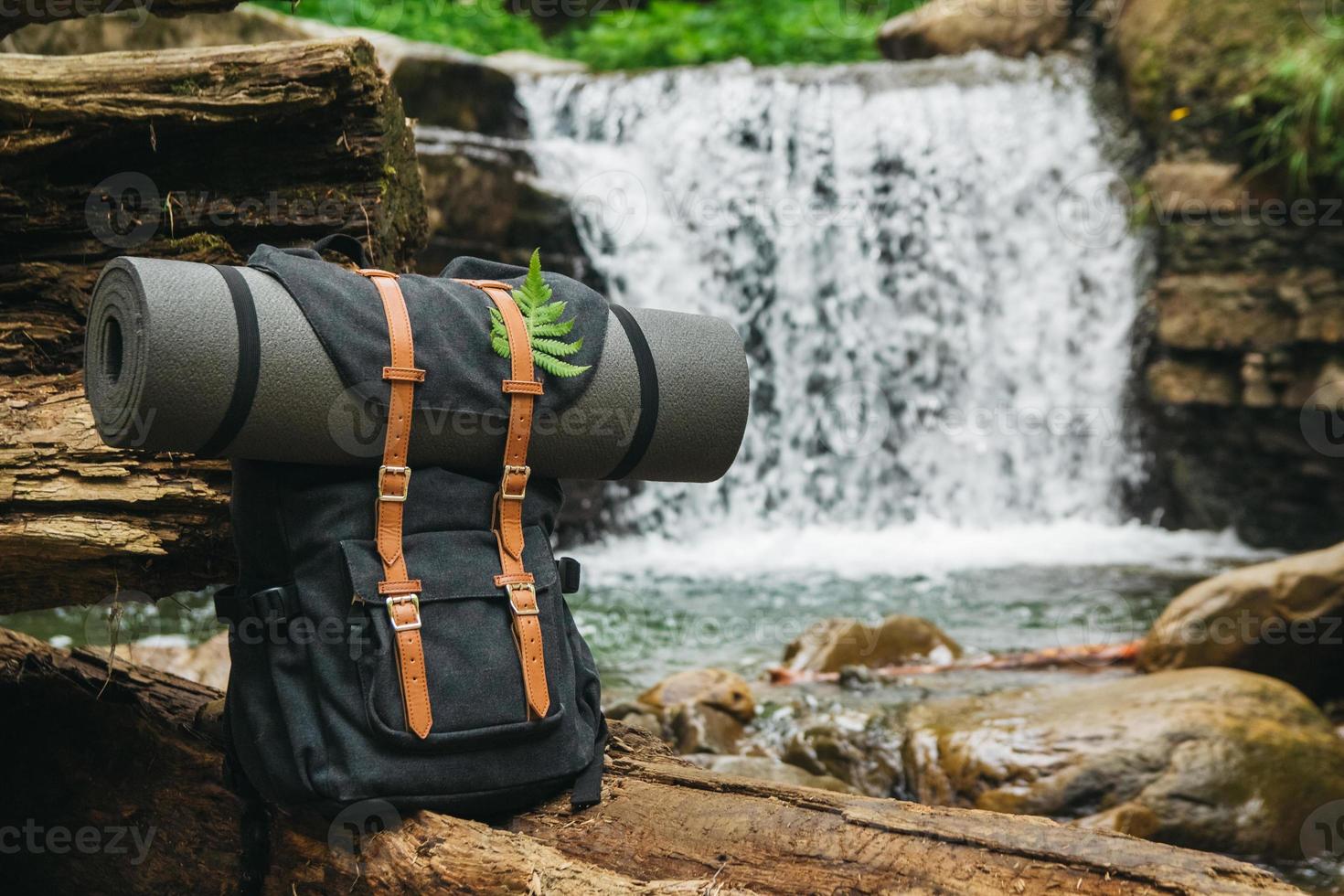 Hipster-Wanderer-Touristenrucksack auf dem Hintergrund von Fluss und Wasserfall foto