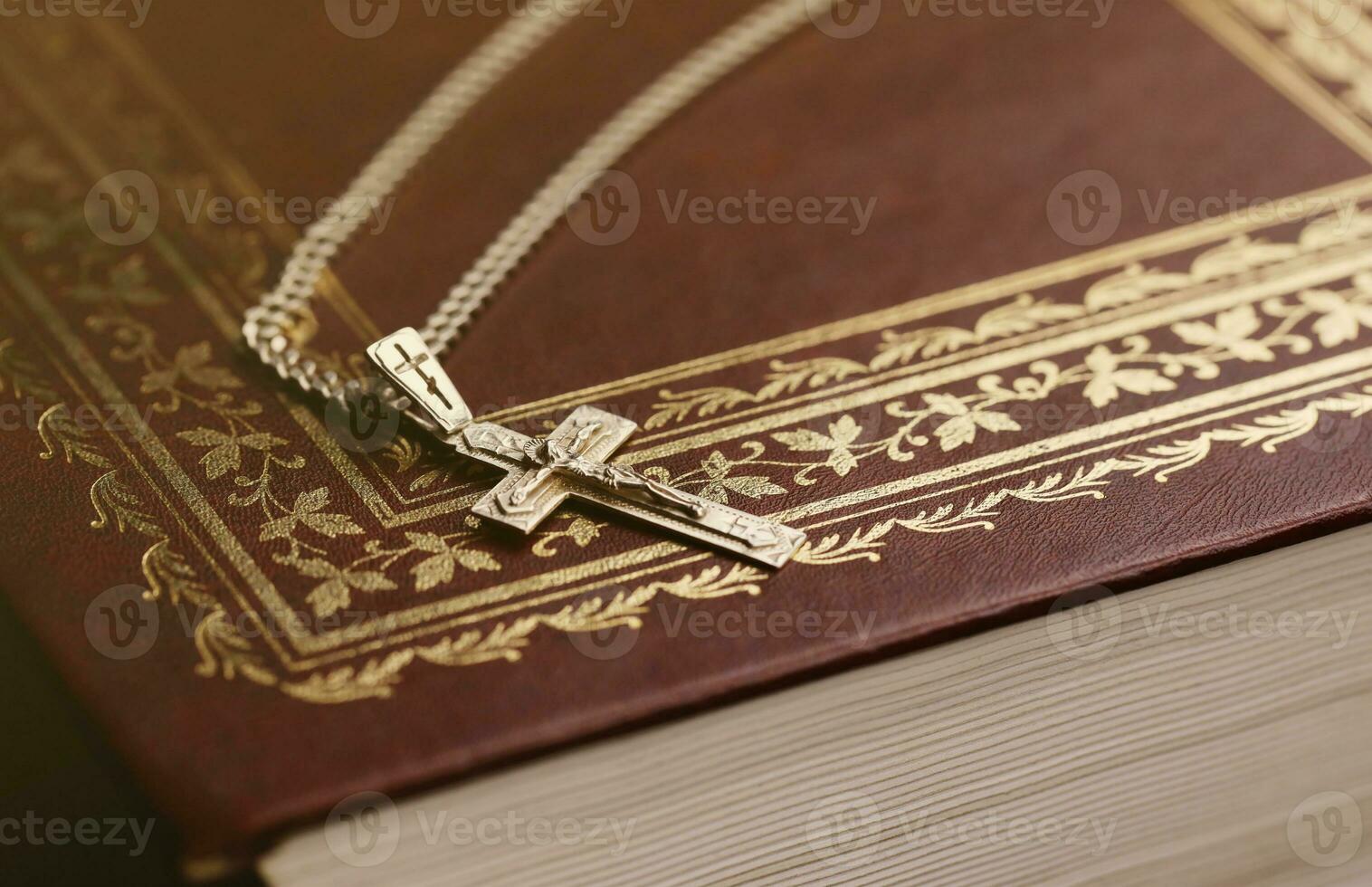 Silberhalskette mit Kruzifixkreuz auf christlichem Bibelbuch auf schwarzem Holztisch. Gott um Segen bitten mit der Kraft der Heiligkeit, die Glück bringt foto