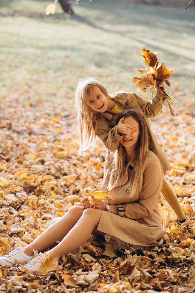 Mutter und ihre Tochter sitzen und haben Spaß im Herbstpark. foto