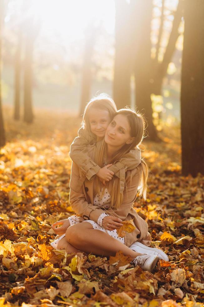 Mutter und ihre Tochter sitzen und haben Spaß im Herbstpark. foto