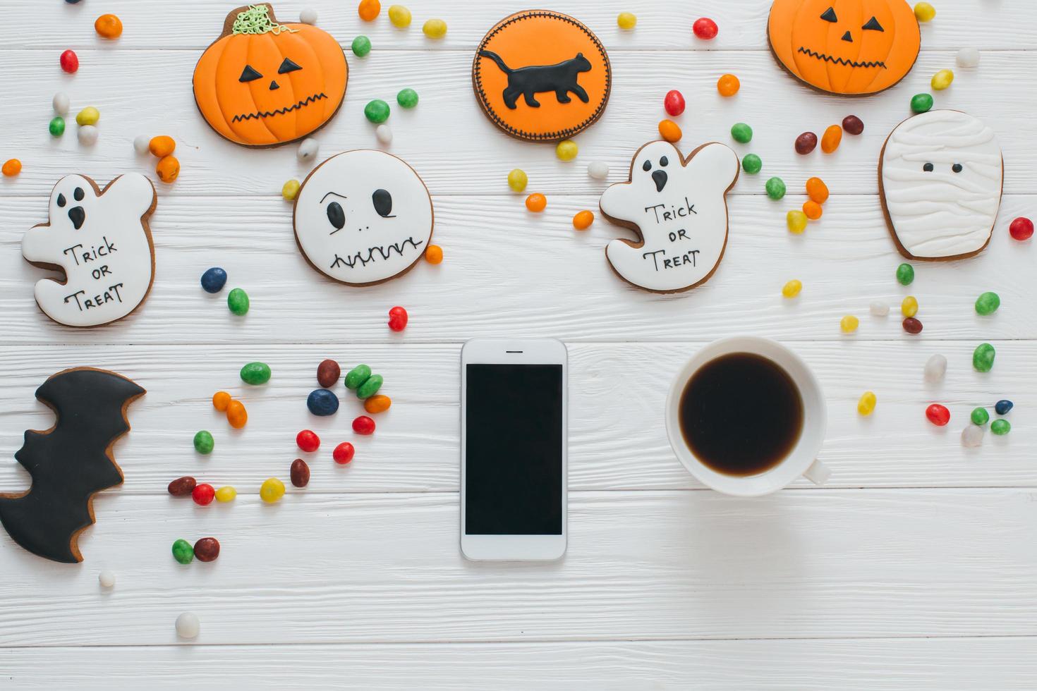 Tasse Kaffee und Smartphone mit Süßigkeiten und Lebkuchen foto