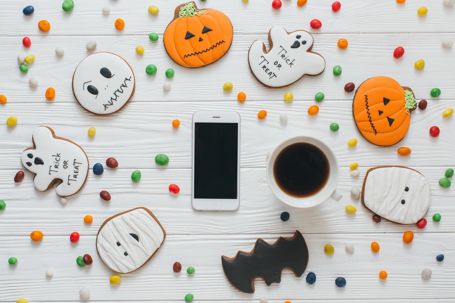 Tasse Kaffee und Smartphone mit Süßigkeiten und Lebkuchen foto
