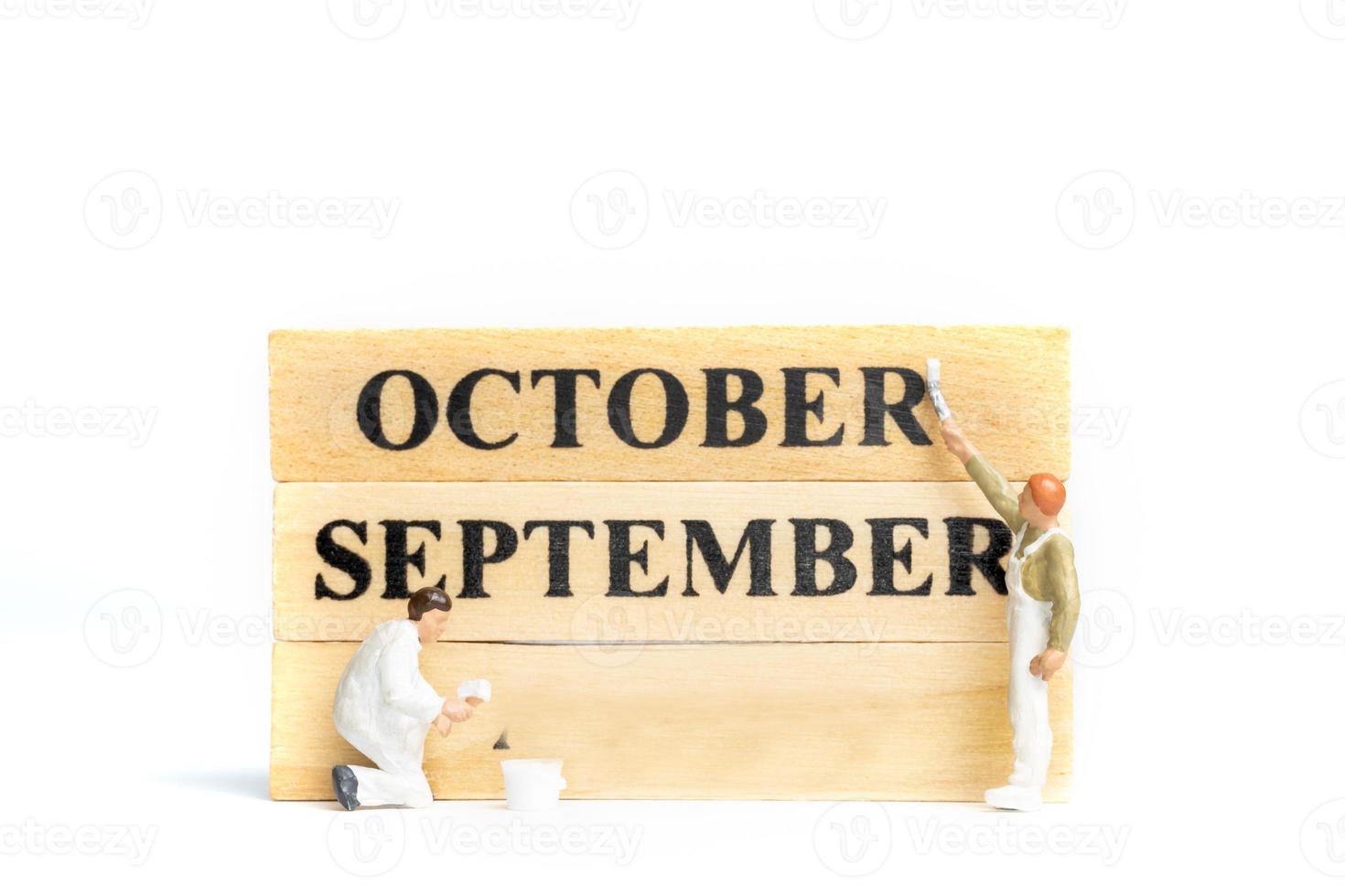 Miniaturmenschen, Arbeiter Malerei Oktober auf Holzblock auf weißem Hintergrund. foto