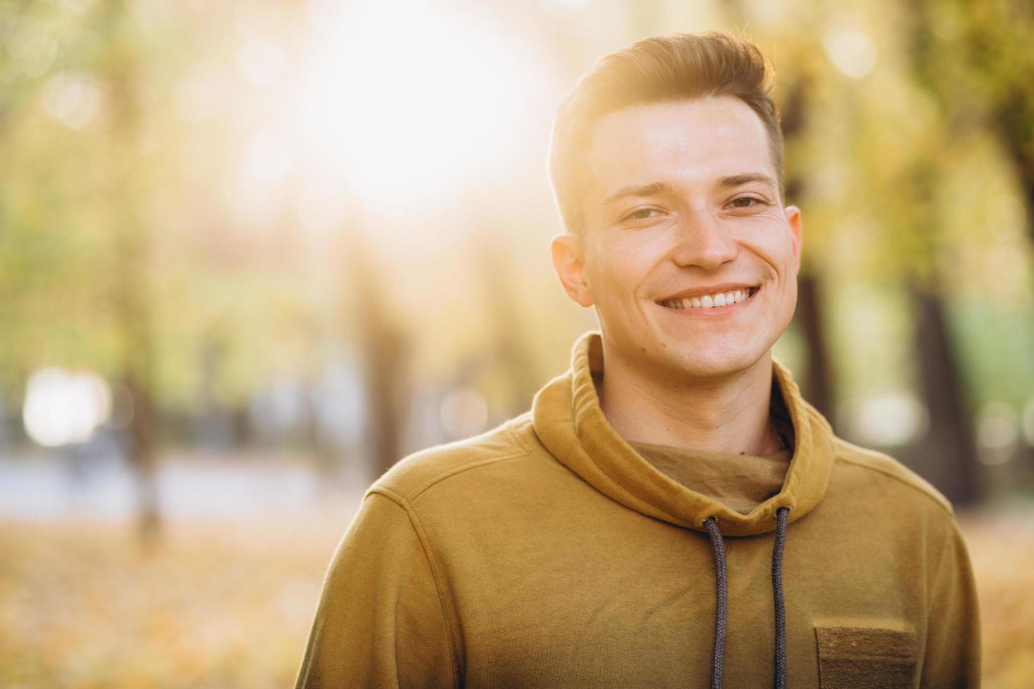 Porträt eines gutaussehenden Mannes, der im Herbstpark lächelt foto