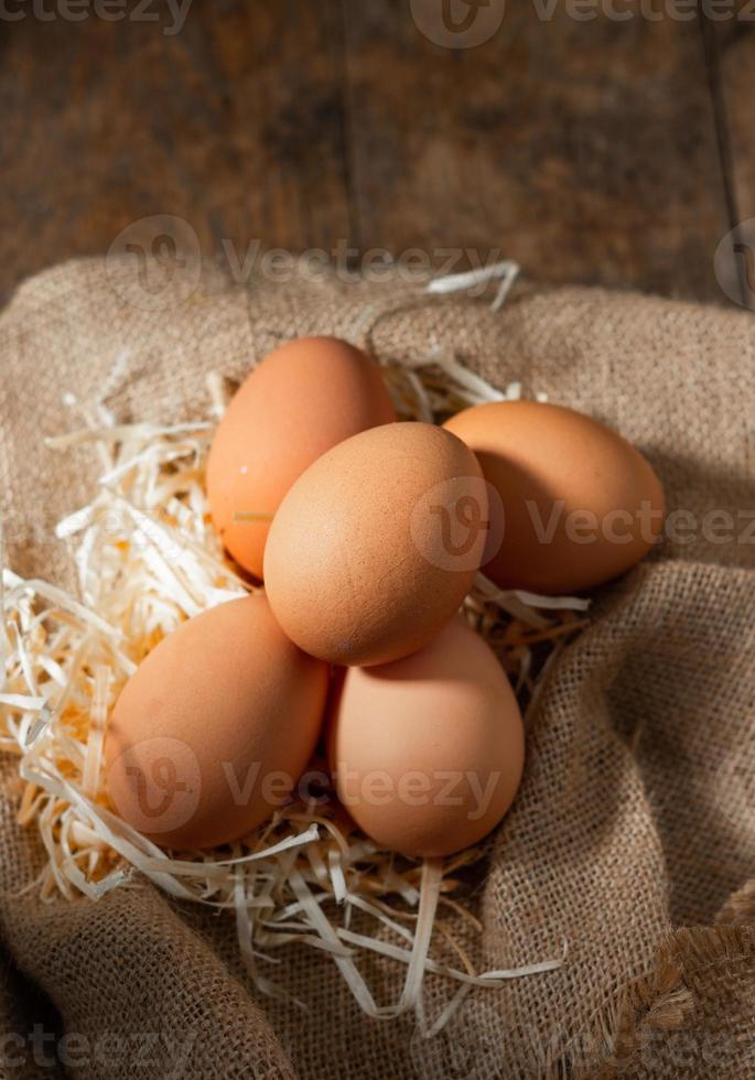 frische Bio-Eier in Sackleinen mit trockenem Gras auf Holztisch foto