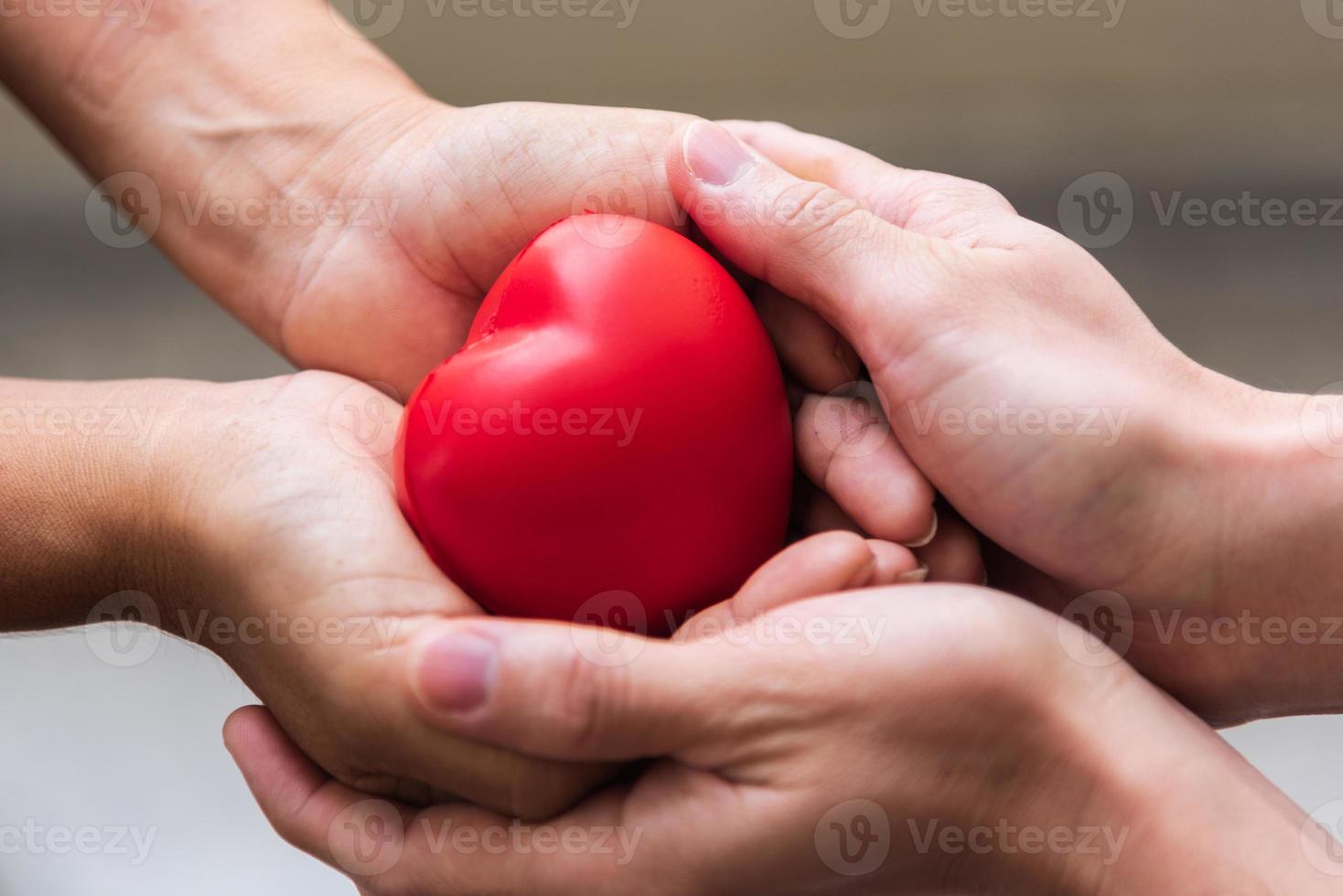 Nahaufnahme Hand, die rotes Herz als Herzspender gibt foto