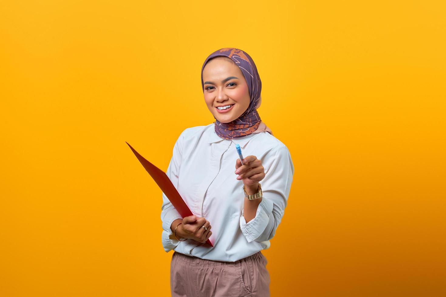 schöne asiatische frau, die ordner hält und mit stift zeigt foto