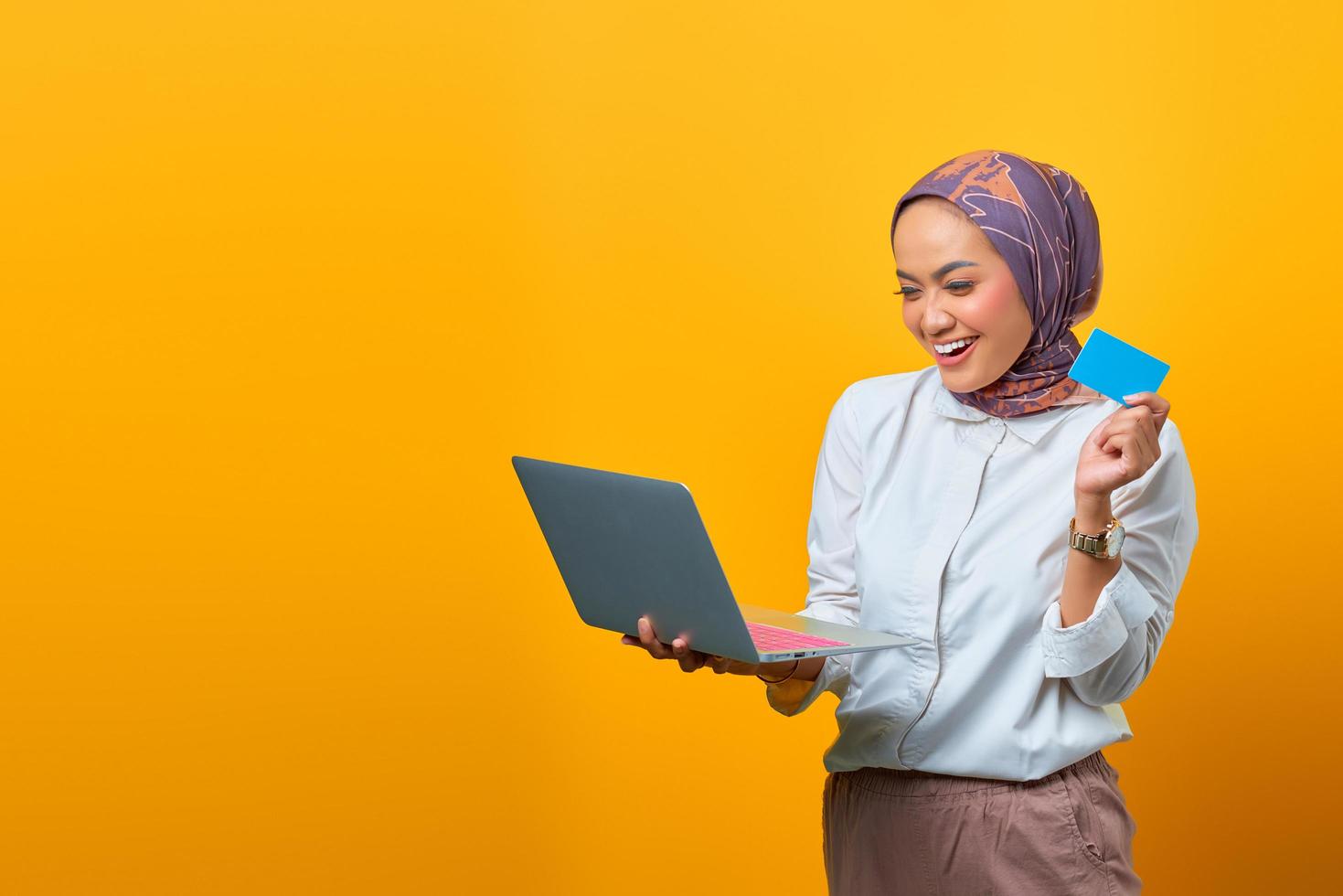 fröhliche asiatische frau, die laptop hält und leere karte zeigt foto