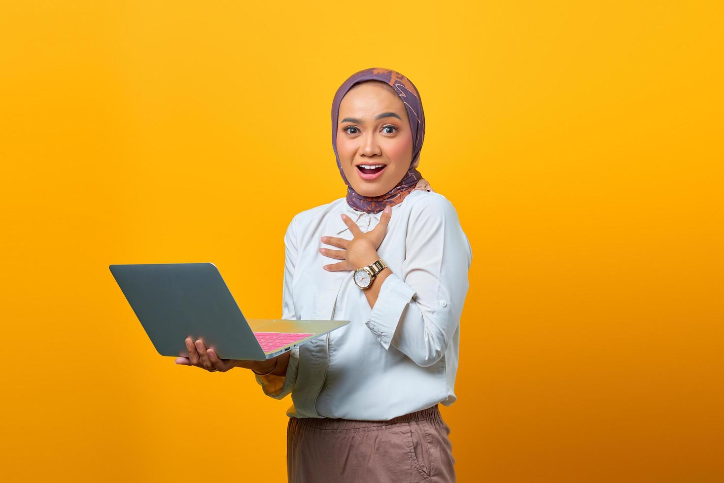 schöne asiatische frau, die laptop mit überraschtem ausdruck hält foto