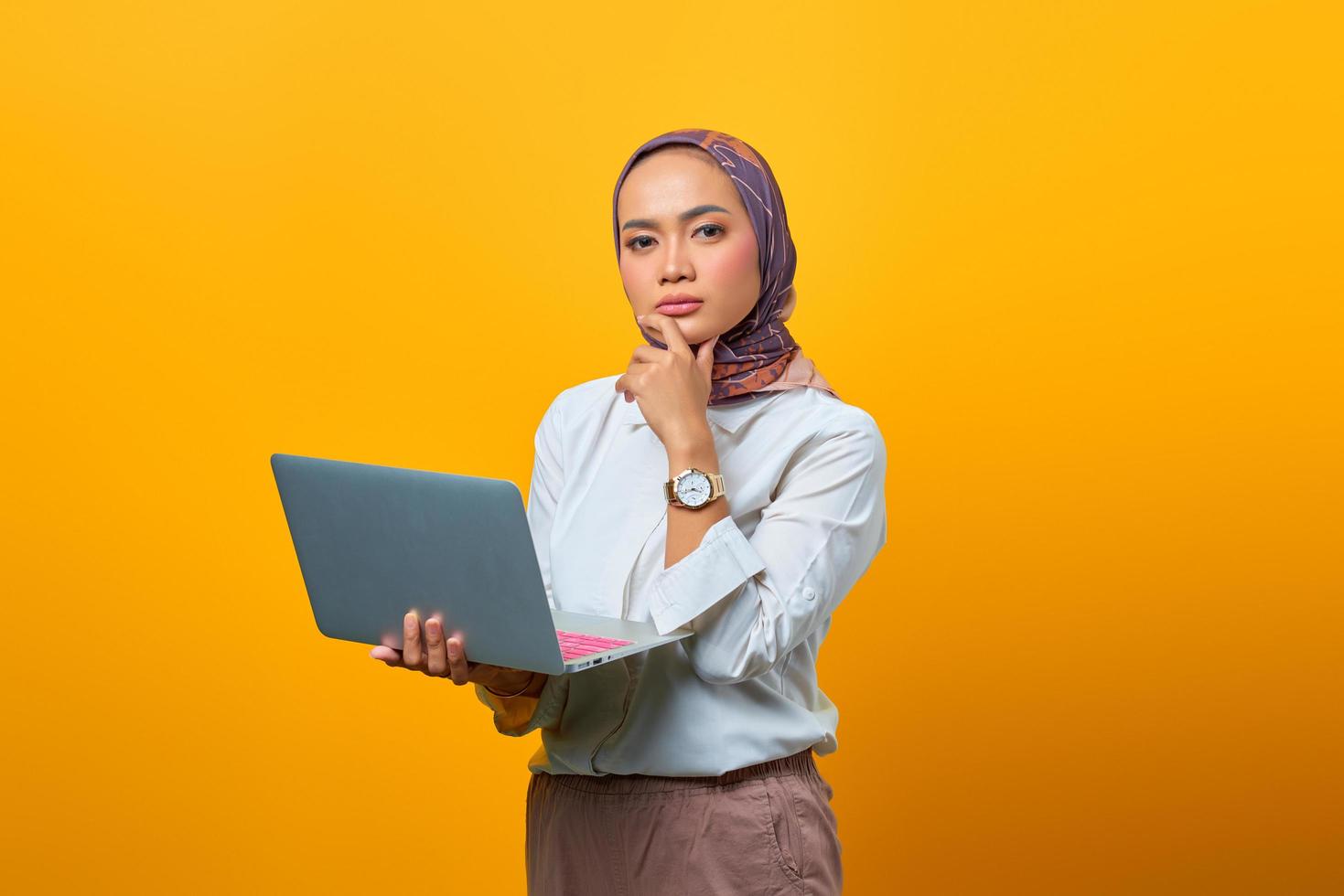 Porträt einer selbstbewussten asiatischen Frau, die Laptop hält und in die Kamera schaut foto