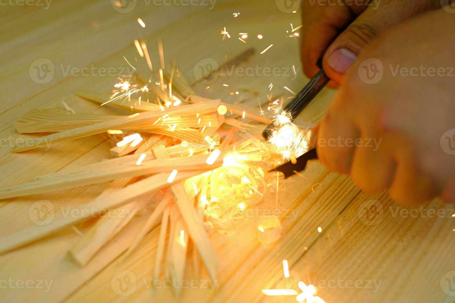 Mann die Hand entzündet ein Feuer mit Feuerstein Magnesium Feuerstahl foto