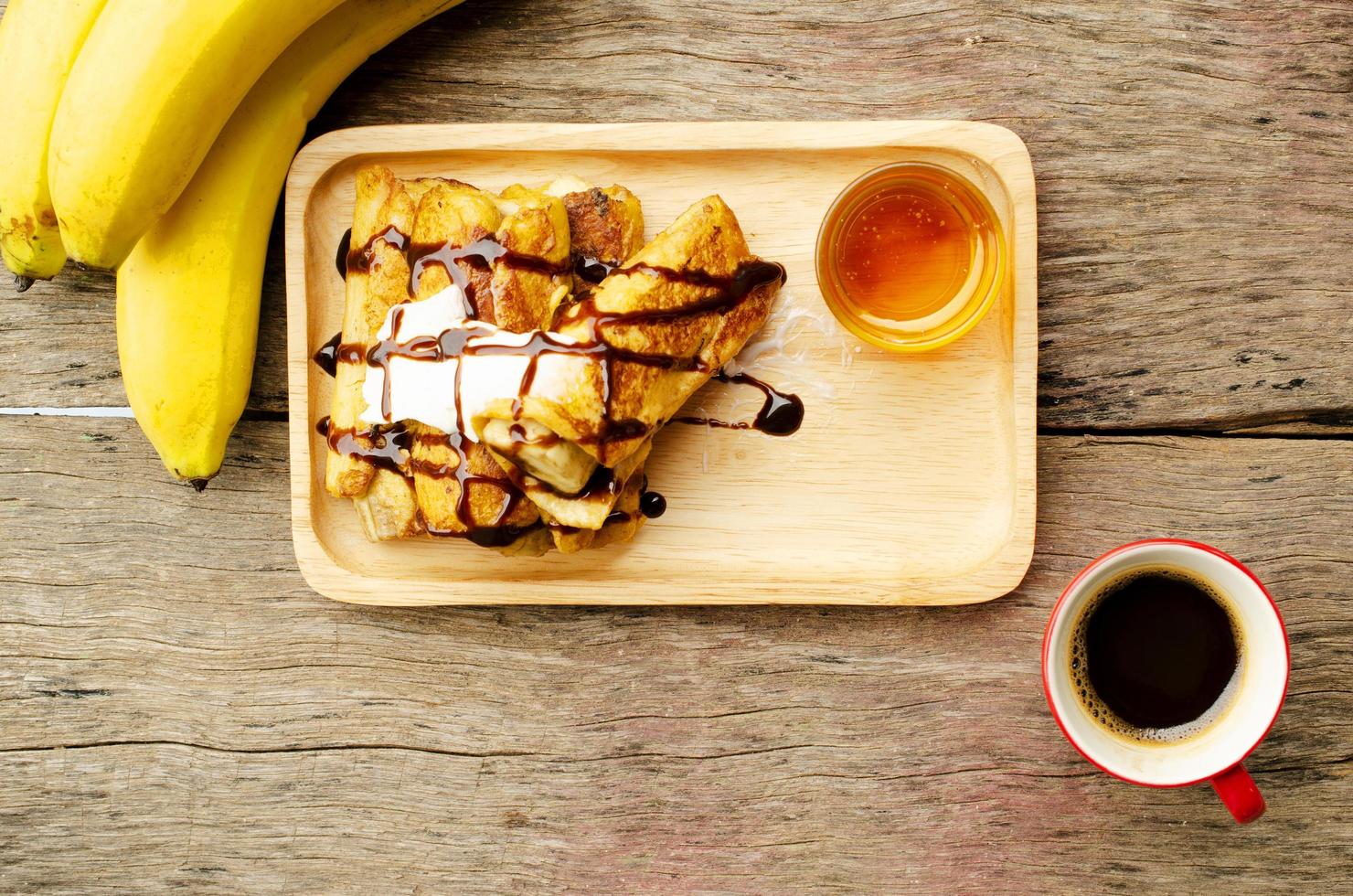 Banane French Toast mit Honig und schwarzem Kaffee rote Tassen auf Holztisch foto