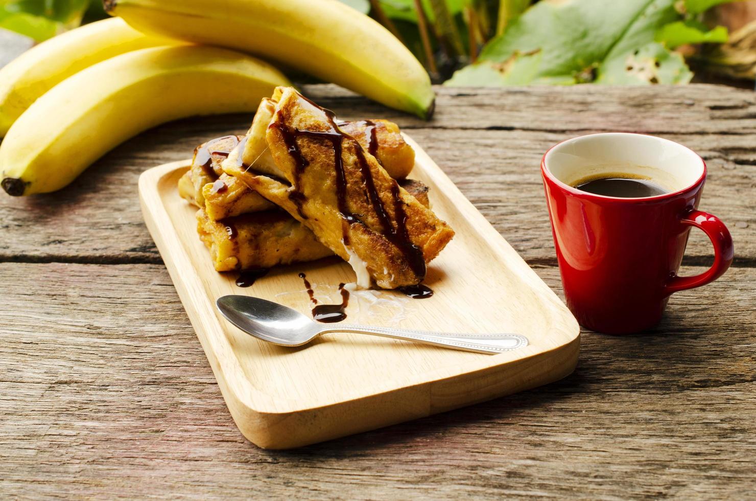 Bananen-French-Toast mit Schokoladen-Tropfsirup und heißer Kaffeetasse foto