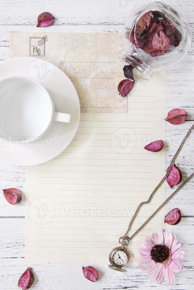 Blumenblätter Briefumschlag Glasflasche Taschenuhr Teetasse foto