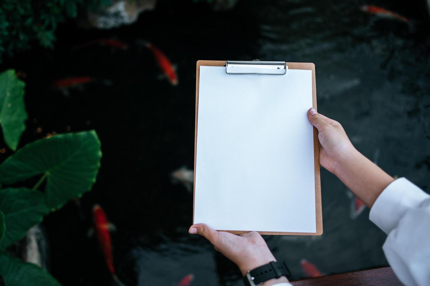 eine Hand, die ein Klemmbrett an einem Fischteich hält foto