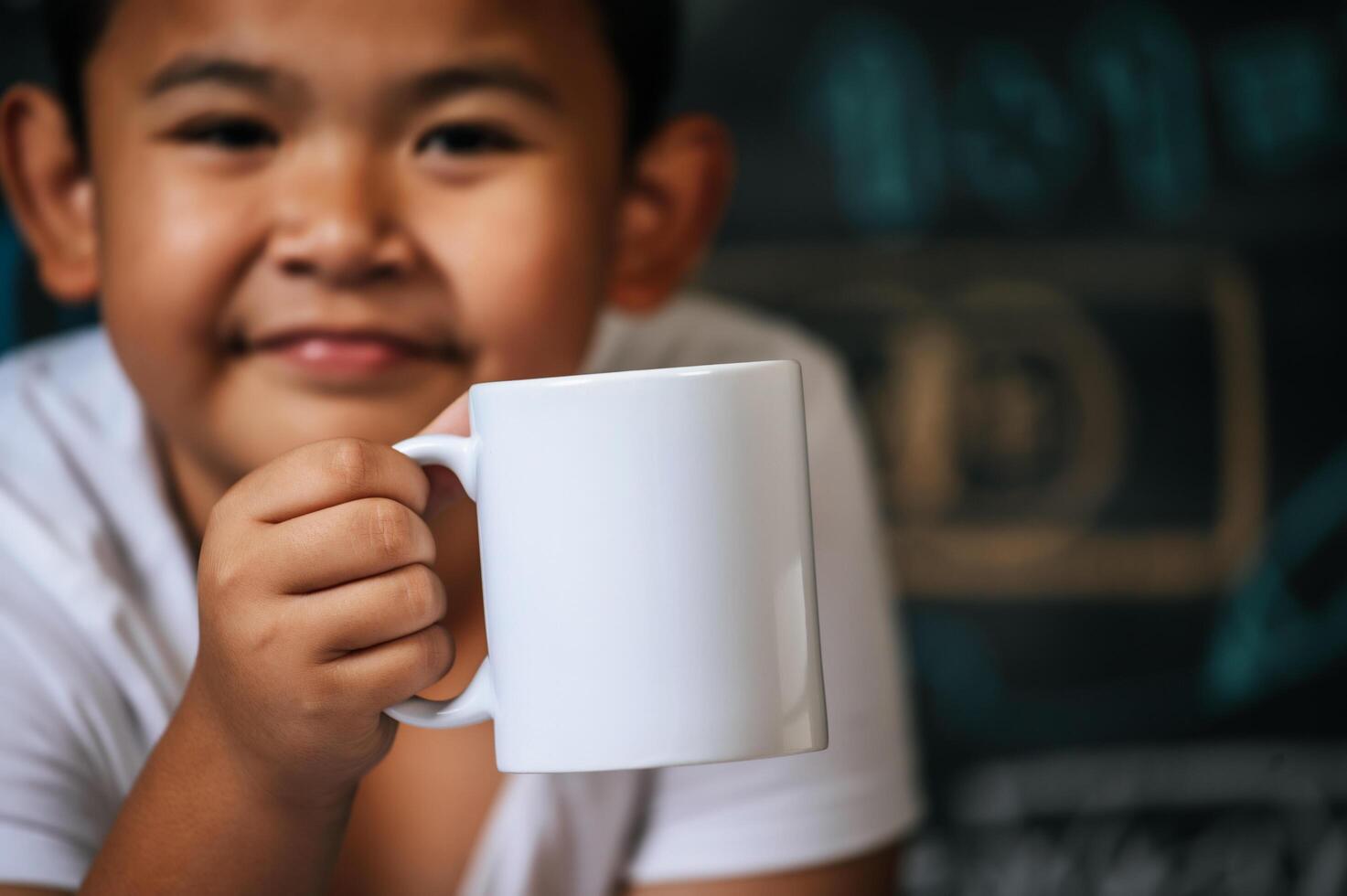 Kind sitzt und hält Tasse im Klassenzimmer foto