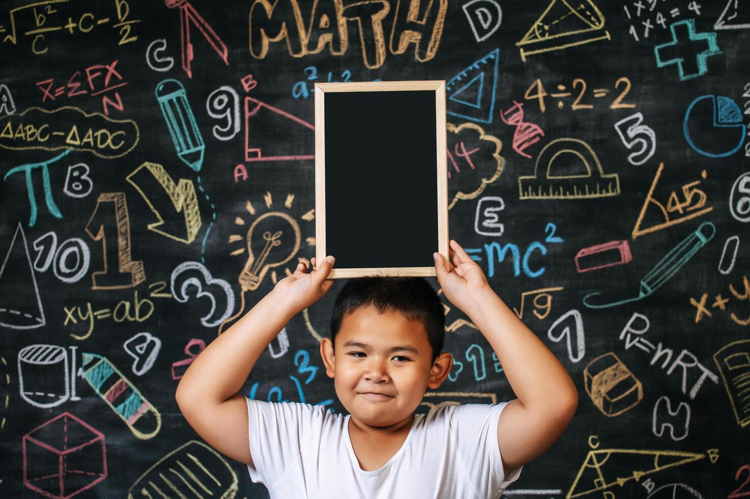 Kind steht und hält Tafel im Klassenzimmer foto