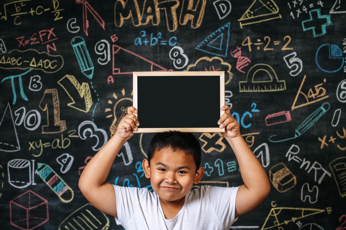 Kind steht und hält Tafel im Klassenzimmer foto