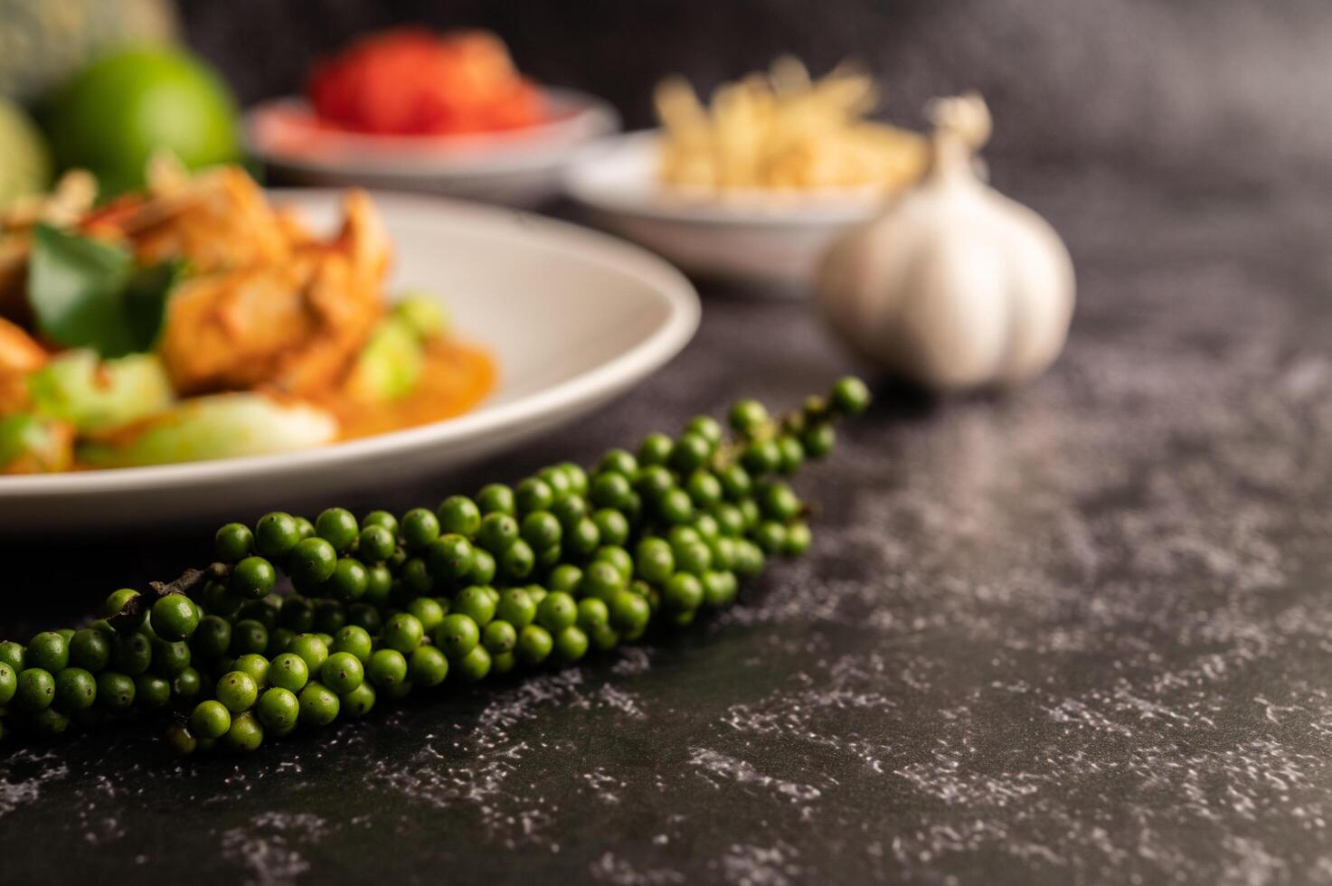 trockenes grünes Curry mit Hühnchen in weißen Tellern auf schwarzem Zement foto