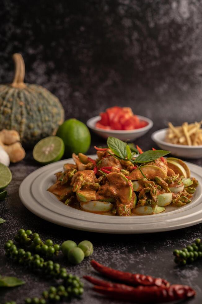 trockenes grünes Curry mit Hühnchen in weißen Tellern auf schwarzem Zement foto