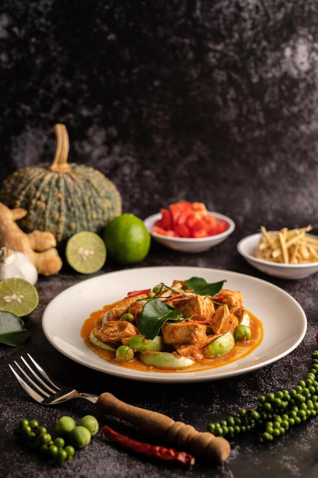 trockenes grünes Curry mit Hühnchen in weißen Tellern auf schwarzem Zement foto