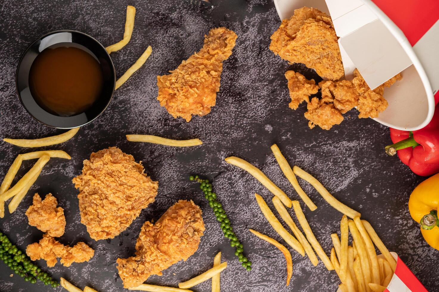 Brathähnchen und Pommes frites auf schwarzem Zementboden. foto