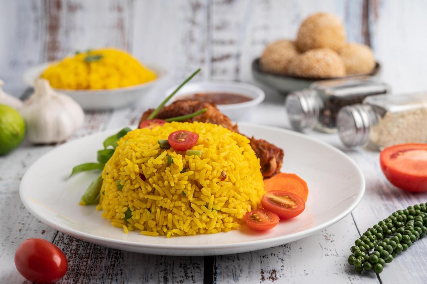 Chicken Biryani in einem Teller mit Gewürzen auf einem weißen Holzboden foto