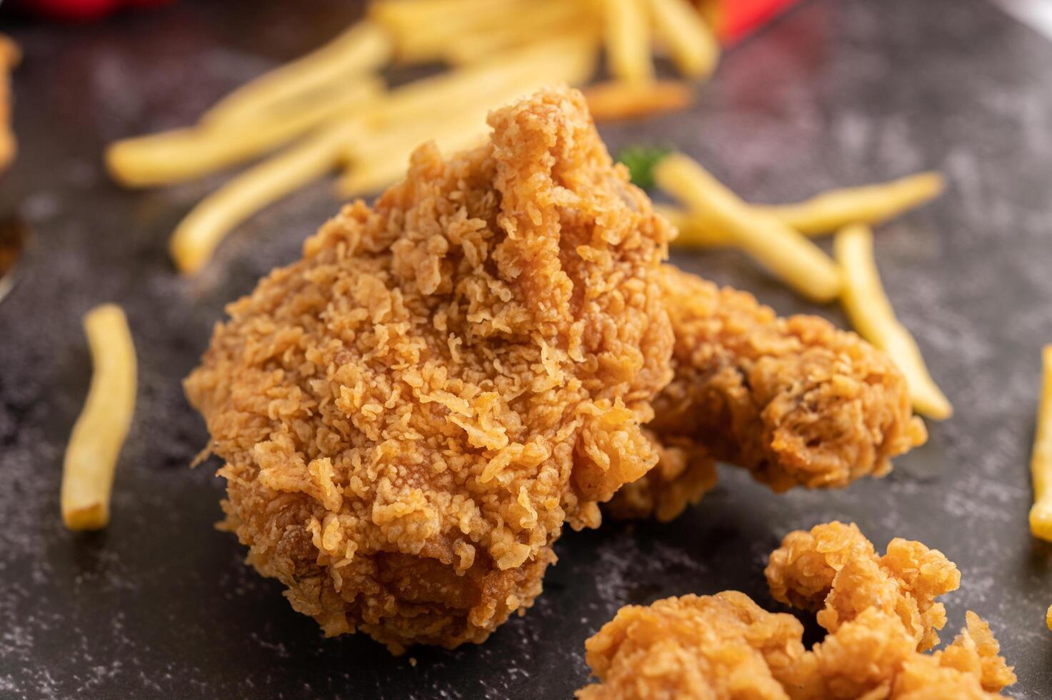 Brathähnchen und Pommes frites auf schwarzem Zementboden. foto