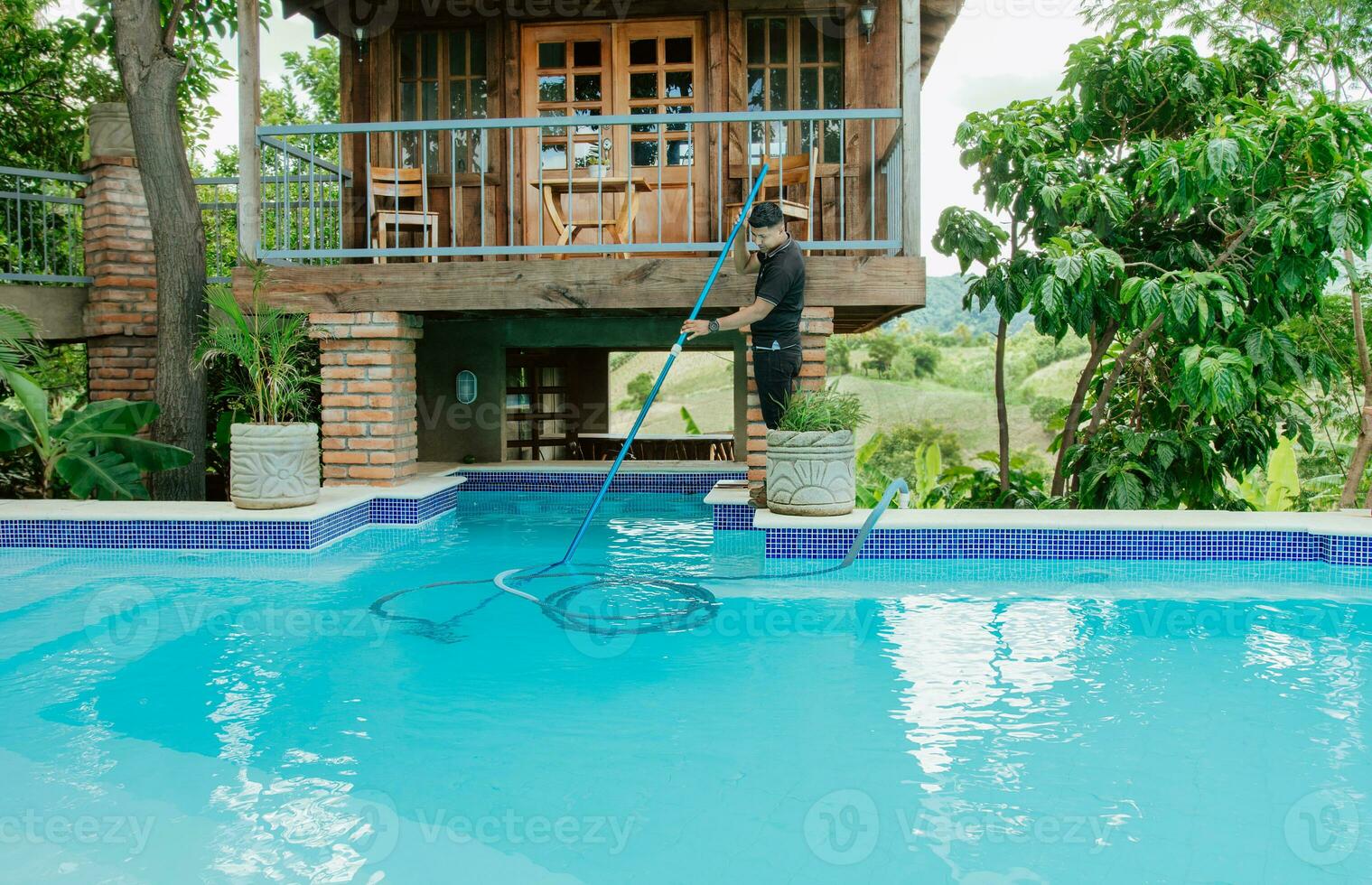Instandhaltung Mann Reinigung Schwimmen Schwimmbad mit Vakuum Absaugen Schlauch. Arbeiter Reinigung ein schön Schwimmen Schwimmbad mit Absaugen Schlauch foto