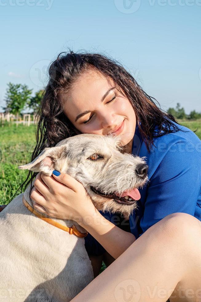 junge fröhliche Frau, die mit ihrem Hund im Park spielt foto